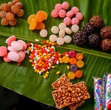 Authentic 90s nostalgic Indian candies laid out on fresh banana leaf featuring Thaen Mittai, Kamarkattu, and Orange drops.